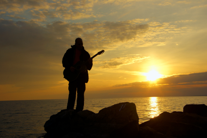 lonely guitarist on the evening beach and sundown